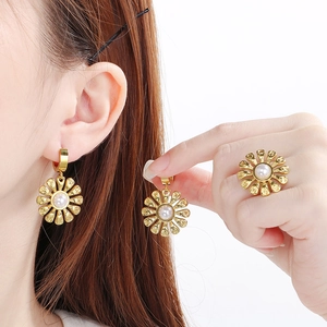 Detail of golden sunflower earrings and ring set with pearl inlay on model