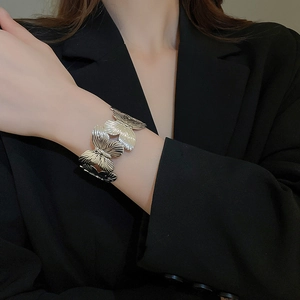 Detail shot of a silver butterfly open cuff bracelet with textured metallic wings on a model