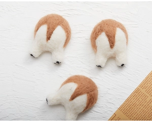 Detailed view of three handmade wool felt Corgi butt ornaments on white textured surface