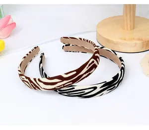 Close-up of zebra and tiger pattern fabric headbands on a wooden display stand
