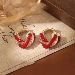 Detailed shot of twisted gold wire earrings with red crystal beads on vintage paper