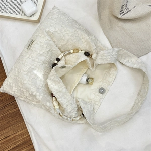 Vue détaillée du sac en dentelle blanche avec poignées décoratives en perles d'ambre et marbre