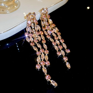 Detailed close-up of long tassel earrings with pink and clear crystals on a golden base