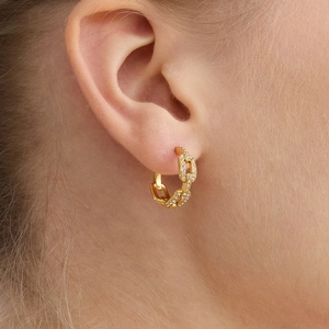 Boucles d'oreilles créoles chaîne dorées avec zircons blancs portées par un mannequin
