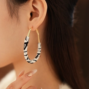 Détail de grandes boucles d'oreilles créoles à motif zébré noir et blanc en tissu
