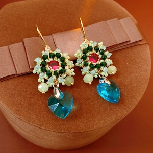 Dettaglio di orecchini a fiore vintage con cuore blu su scatola di velluto