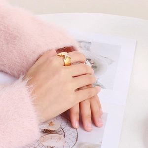 Close-up of golden X-shaped crossover ring with sparkling crystals on a female hand