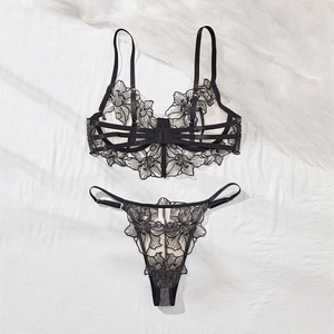Close-up of black floral lace embroidery lingerie set with strappy details on white fabric