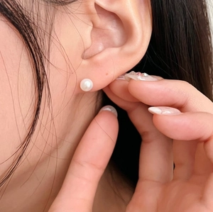 Close-up of 12mm white pearl stud earring on ear showing elegant luster and smooth finish