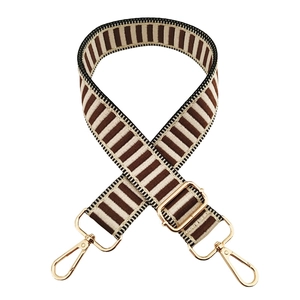 Detailed view of adjustable wide striped shoulder strap with gold metal rotating hooks
