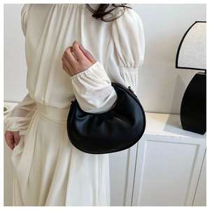 Detail of minimalist black crescent shoulder bag with pleated leather and gold hardware