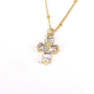 Detailed macro view of a gold cross pendant inlaid with sparkling square zircons