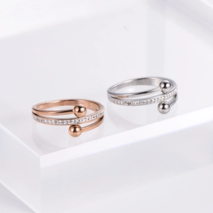 Minimalist silver and rose gold criss-cross rings with pavé set crystals on a white pedestal