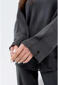 Detailed close-up of distressed knit cuffs and hem on a dark grey sweater set