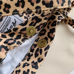 Detailed close-up of leopard print canvas bag with vintage metal magnetic buckle and woven label