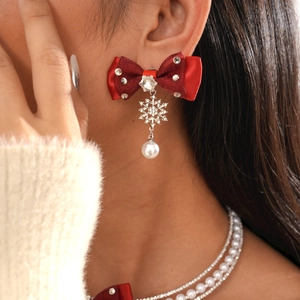 Close-up of festive red ribbon bow earrings with diamond snowflake and pearl charms
