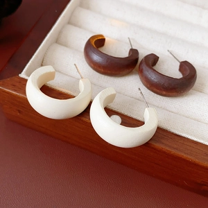 Detail of minimalist C-shape wooden earrings in dark brown and white in a velvet jewelry box