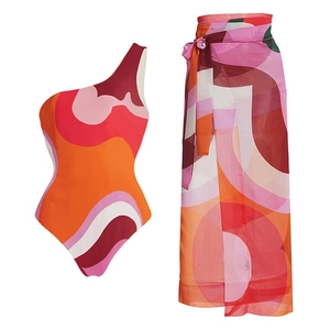 Detail of one-shoulder one-piece swimsuit set with geometric print and matching wrap skirt