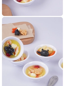 Close-up of miniature chicken soup bowls with wolfberries and herbal ingredients