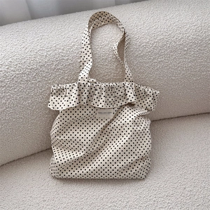 Detailed view of the ruffle edge and polka dot canvas fabric with a brand textile label