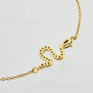 Macro shot of gold snake-shaped bracelet with pave zircon details and link chain