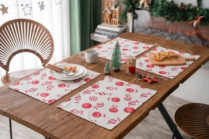 Set of 4 Christmas placemats with festive red candy and ornament print on wooden table