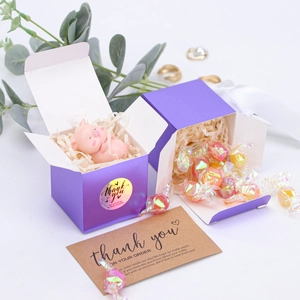 Close-up of purple square gift box for candies with thank you stickers and shredded paper
