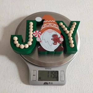 Detail of wooden Christmas JOY sign showing gingerbread dwarf on weighing scale