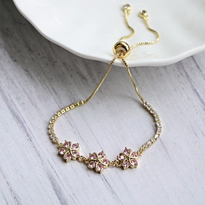 Bracciale dorato regolabile con fiori in zircone rosa e dettagli in cristallo bianco