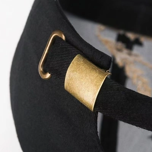 Dettaglio della fibbia regolabile in bronzo e trama del tessuto su un cappello nero