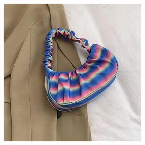 Close-up of rainbow gradient pleated shoulder bag with satin texture on blazer background