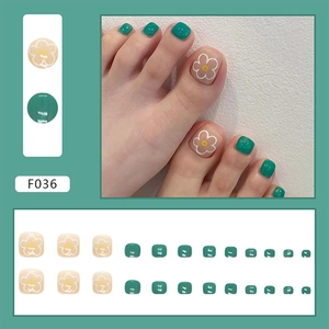 Detailed set of 24 green and beige press-on toenails featuring delicate white floral patterns