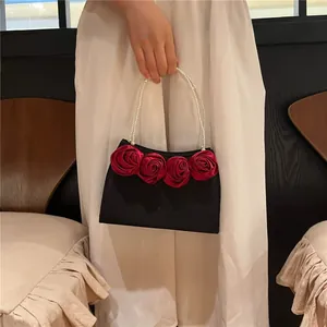 Detail of vintage black handbag with satin red roses and elegant pearl top handle