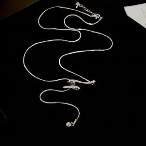 Sleek silver snake chain necklace with abstract geometric pendant and metallic ball charm