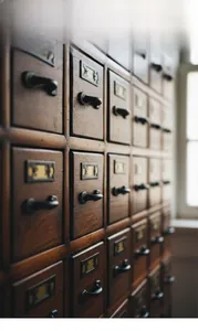 Detail of vintage wooden cabinet featuring black metal handles and retro label frames