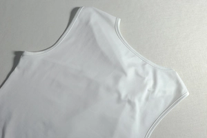 Close-up of white knitted fabric with precise double-needle stitching on the neckline