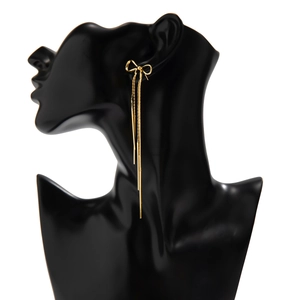 Detailed side view of golden bow tassel earrings on model with long hanging chains