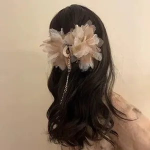 Detail of cream mesh flower hair claw with sparkling rhinestone tassel in long wavy hair
