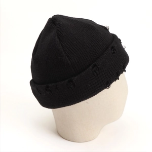 Detail of black knit beanie featuring silver metal rings and distressed torn fabric texture