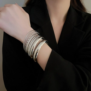 Détails de bracelets argentés superposés aux textures variées sur un mannequin