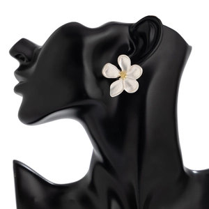 Close-up of white five-petal flower earrings with gold center on a black mannequin