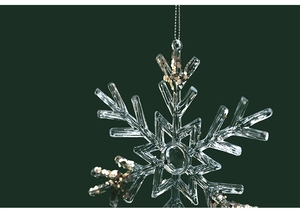 Detailed macro view of a clear acrylic snowflake ornament with sparkling gold glitter accents