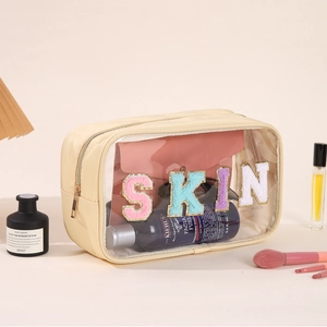 Detail view of transparent PVC makeup bag with SKIN patches and golden zipper closure