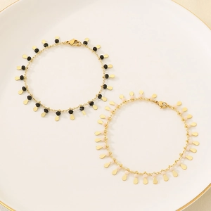 Elegant gold-tone beaded bracelets with colorful charms displayed on a ceramic tray