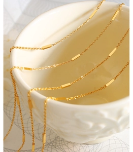 Detailed view of a gold O-chain necklace with polished rectangular bar accents on a cup