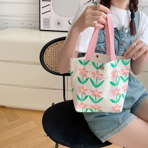 Dettaglio della borsa in tela floreale con manici rosa e etichetta del marchio