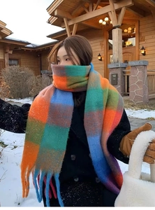 Close-up of rainbow plaid scarf with long tassels in a snowy outdoor winter setting