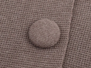 Macro detail of high-quality brown knitted cardigan with a fabric-covered button