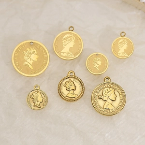 Set of seven golden stainless steel Queen Elizabeth II coin pendants on textured fabric