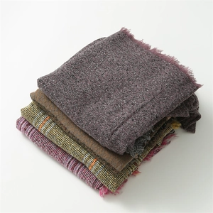 Close-up of stacked cashmere-like scarves in purple, brown, and plaid with fringe details